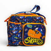 Front view of a blue and orange kids insulated lunch bag featuring a skateboarding dinosaur pattern and a textured chenille dinosaur graphic on the front zippered pocket.