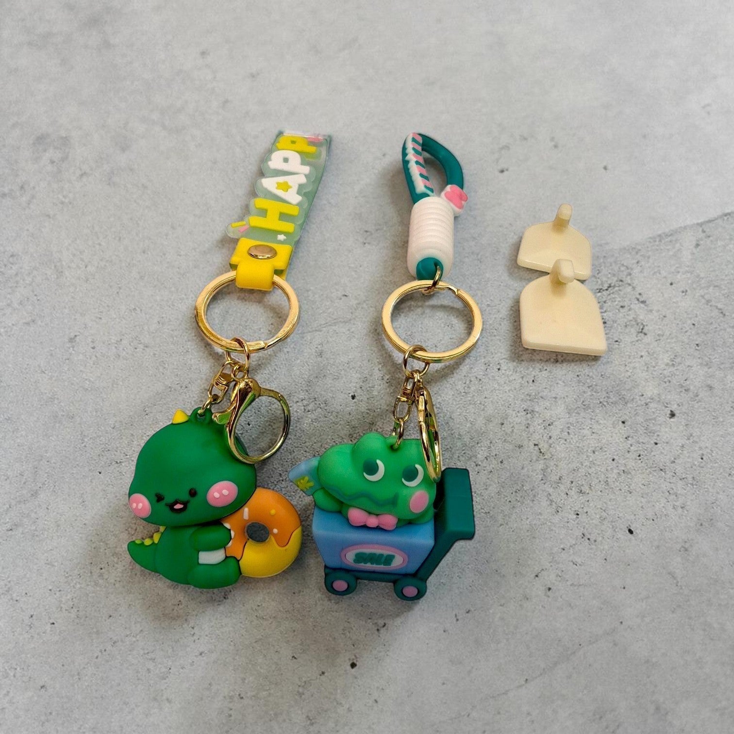 Tiny Tokens green dinosaur with donut and green alligator in shopping cart 3D rubber keychains with gold hardware.