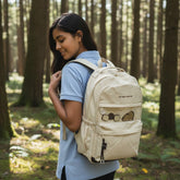 Tiny Tokens cream canvas backpack with capybara and cookie charms, transparent front pocket, and multiple compartments.