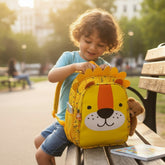 Tiny Tokens yellow polyester toddler backpack with 3D lion face and mane, roar print, and side pockets.