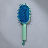 Tiny Tokens mint green and blue oval cushion hair brush with soft flexible bristles and hanging loop.