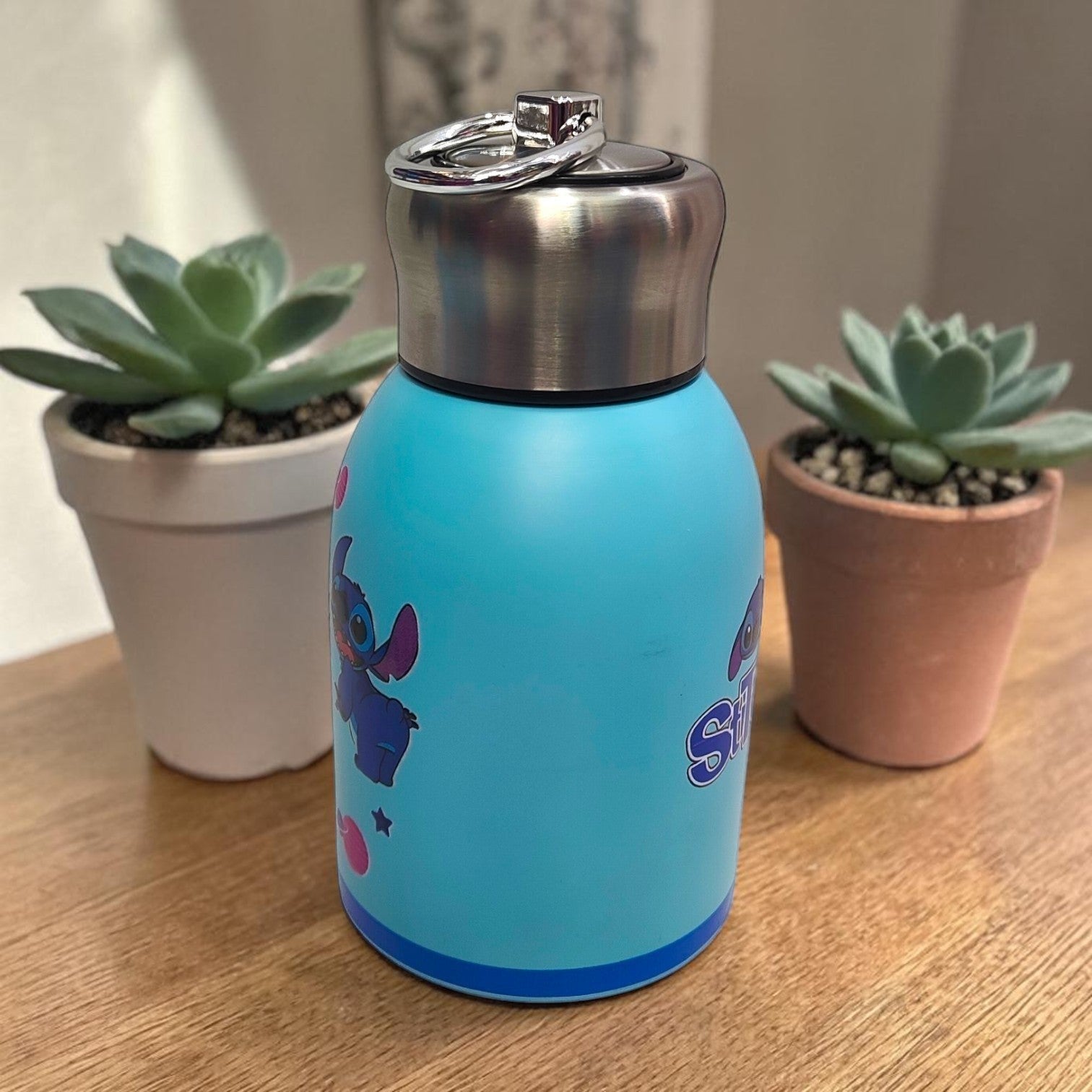 Tiny Tokens sky blue Stitch mini insulated steel water bottle with screw cap and metal loop. Features cute Stitch graphics and planets.
