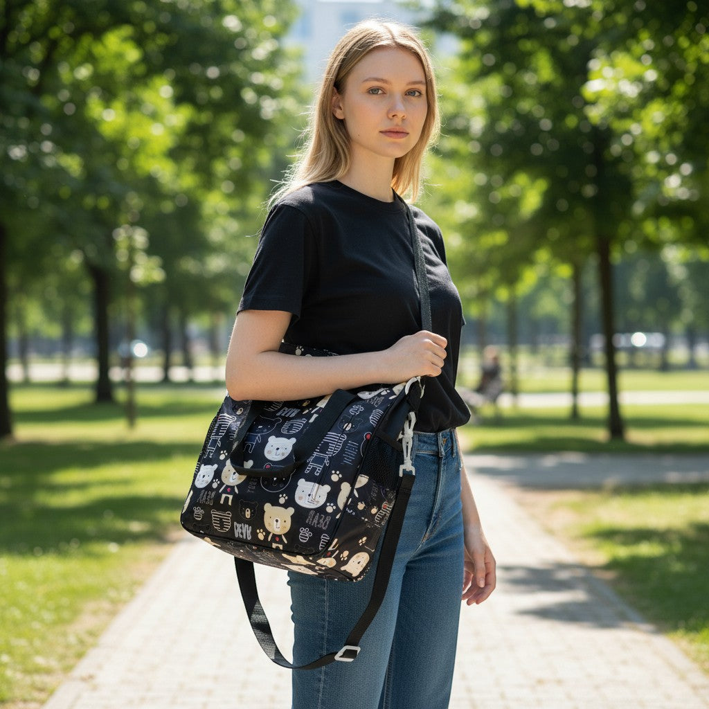 Tiny Tokens black tote bag with a cute all-over teddy bear print, featuring a stroller strap and shoulder strap.