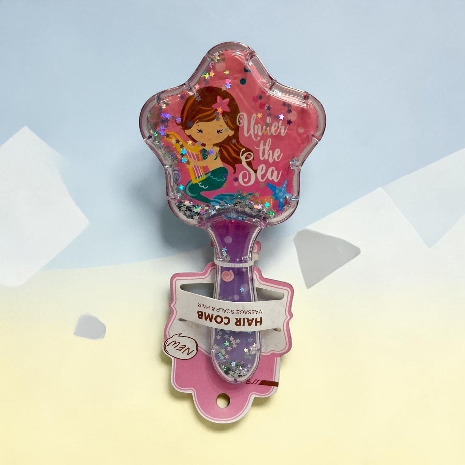 Tiny Tokens kids' star-shaped hair comb with mermaid design and floating glitter. Features pink bristles and a purple handle.