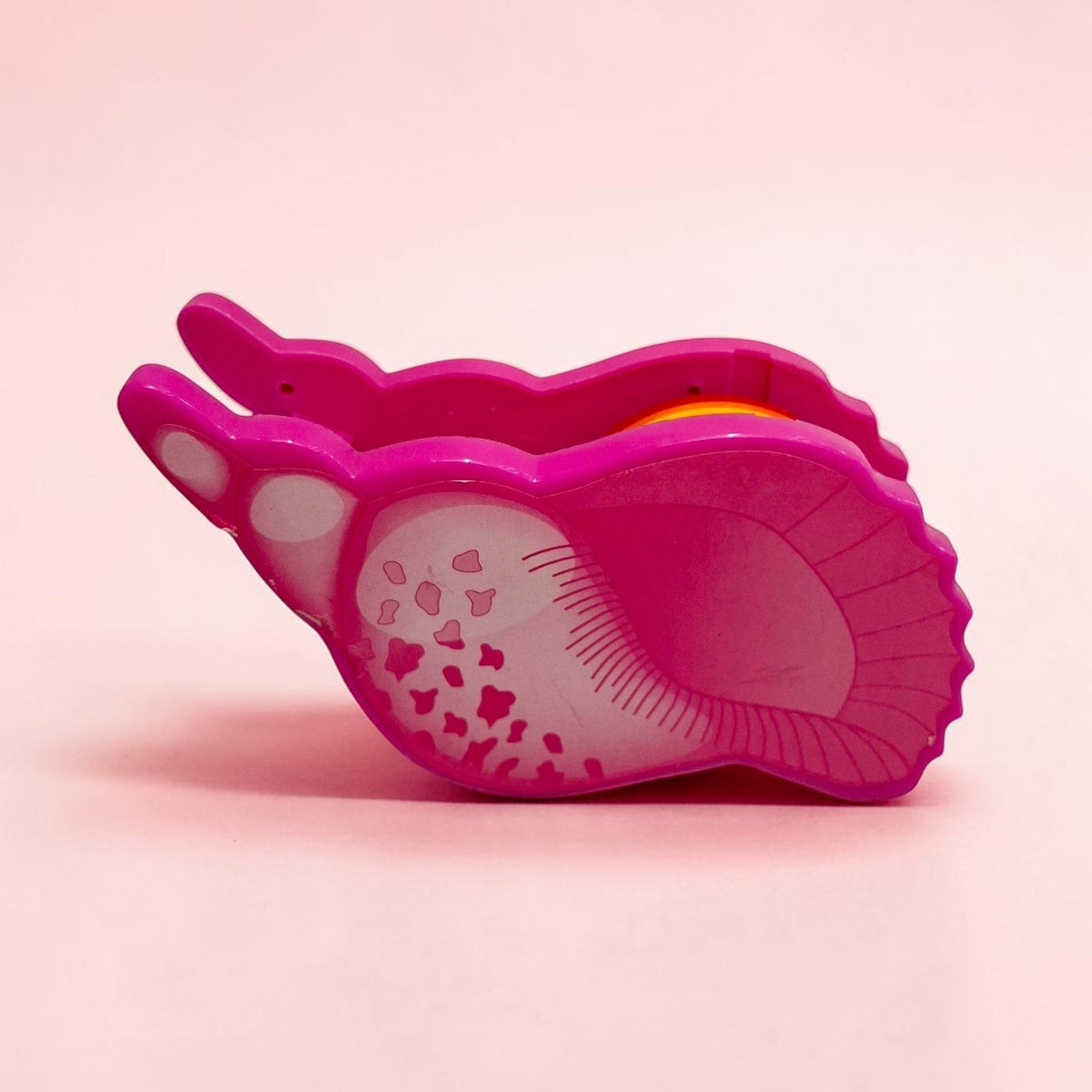 Tiny Tokens pink dinosaur paw tape dispenser made of ABS plastic with a rainbow tape roll.