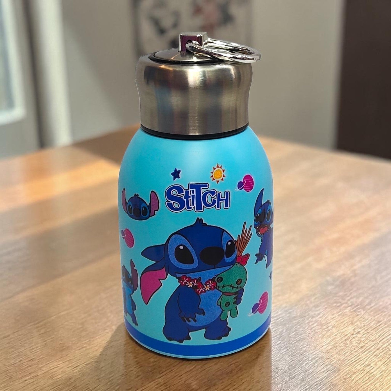 Tiny Tokens sky blue Stitch insulated steel water bottle with screw cap and loop, featuring multiple Stitch poses and planets.