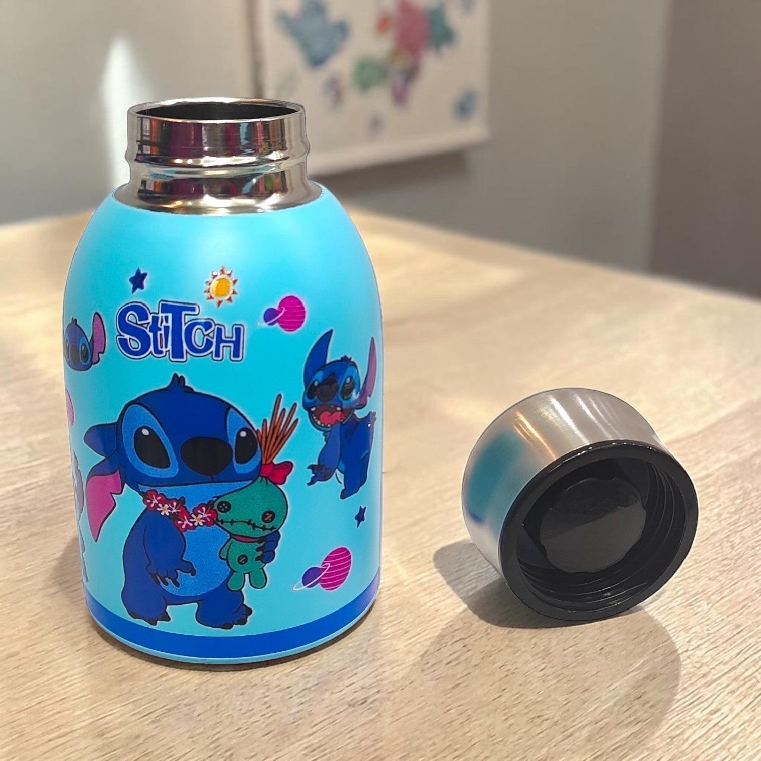 Tiny Tokens sky-blue insulated steel water bottle for kids featuring Stitch characters and planets. Includes a screw-on steel cap.