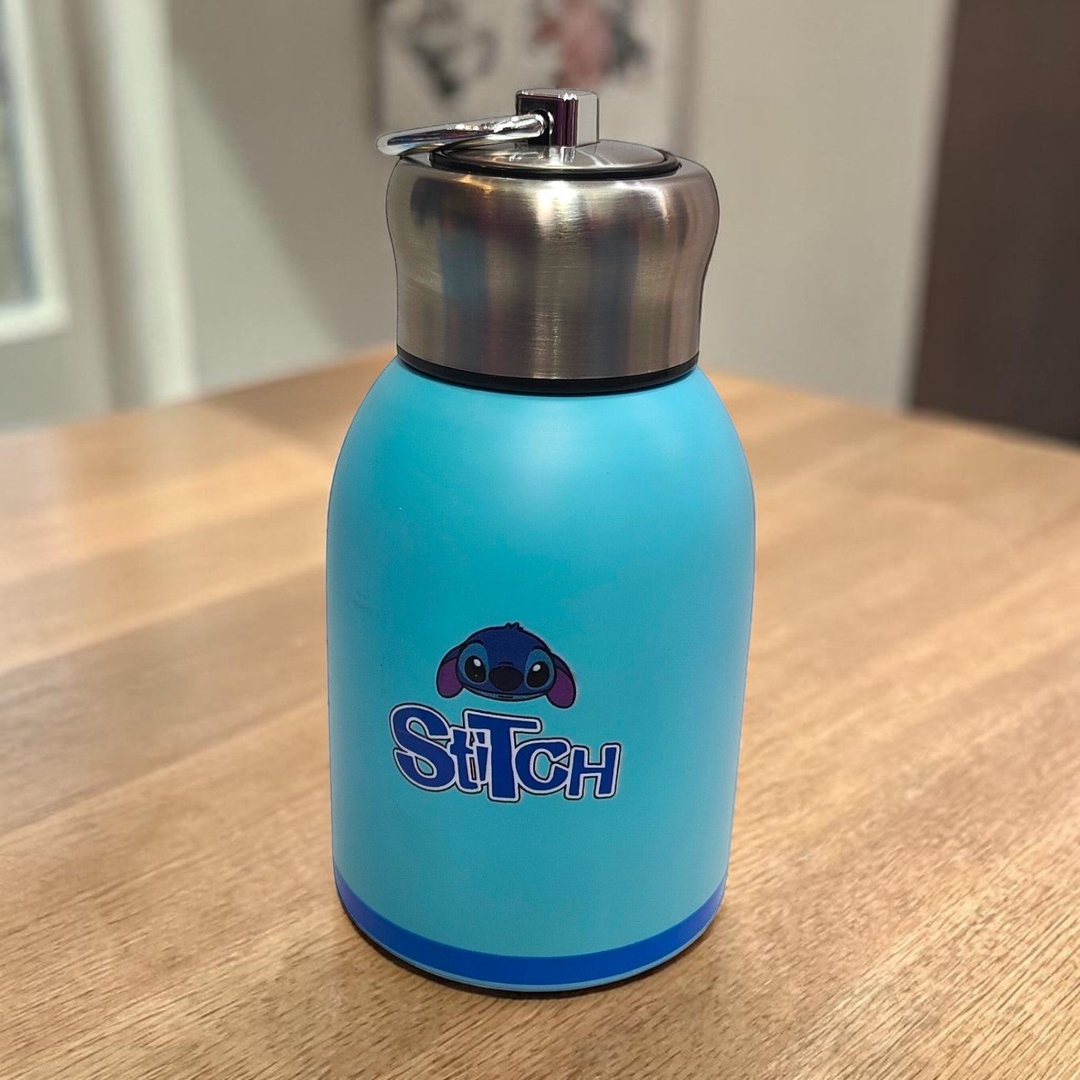 Tiny Tokens sky blue Stitch mini insulated steel water bottle with screw cap and metal loop. Features Stitch character graphic and lettering.