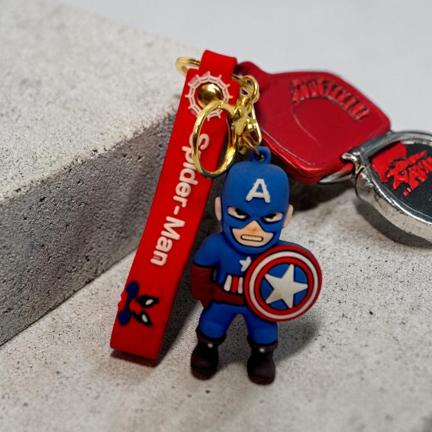 Tiny Tokens Captain America 3D rubber keychain with red strap and gold hardware. Perfect for bags and keys.