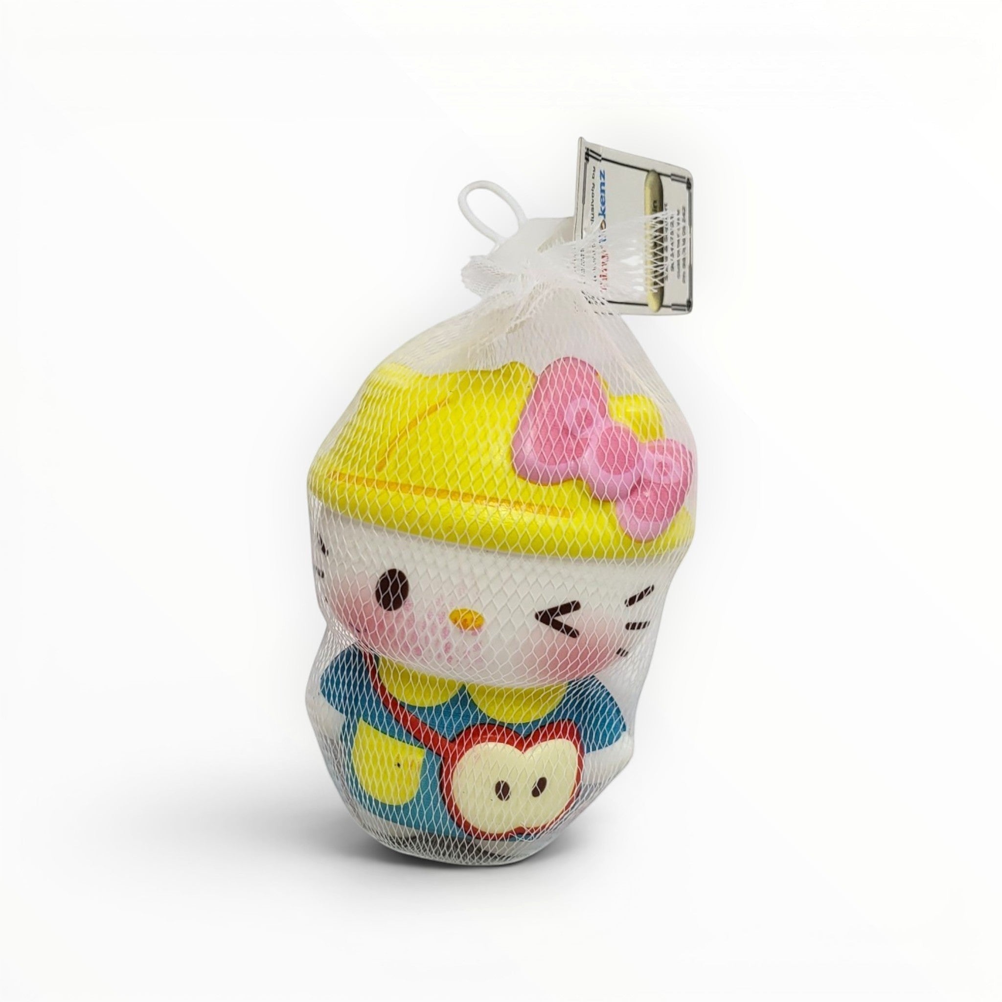 Tiny Tokens white cat squishy toy with pink bow and yellow hat, wearing a blue outfit with an apple detail. Soft rubber stress toy.