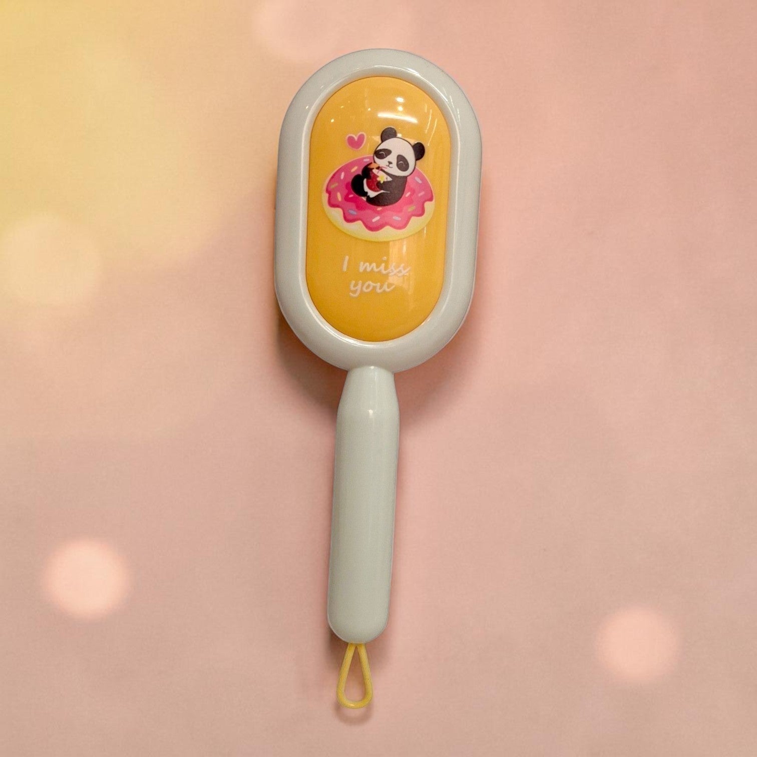 Tiny Tokens cream-beige cushion hair brush with a panda on a pink donut design and 'I miss you' text. Features soft bristles for detangling.