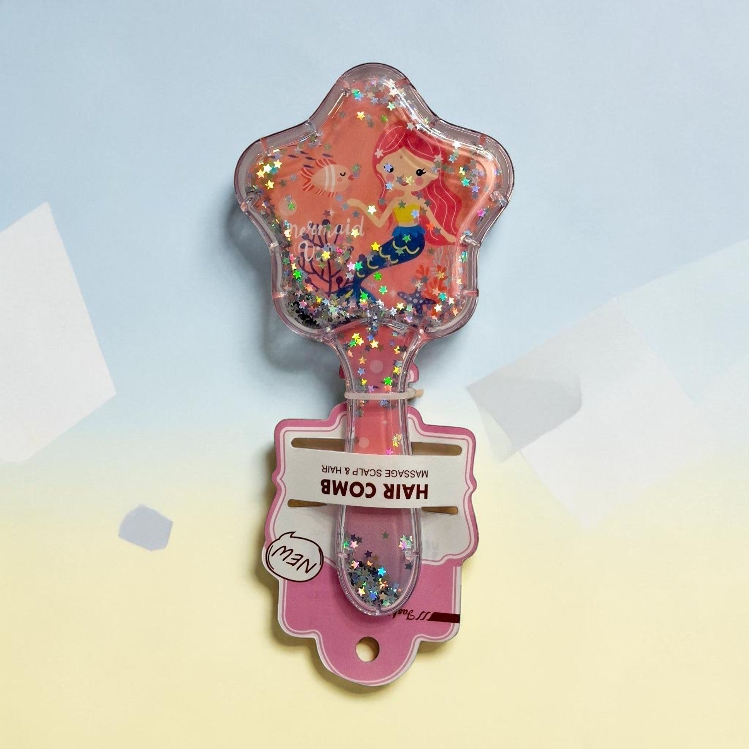 Tiny Tokens kids mermaid hair comb with star-shaped head, floating glitter, and soft pink bristles. Features mermaid artwork.