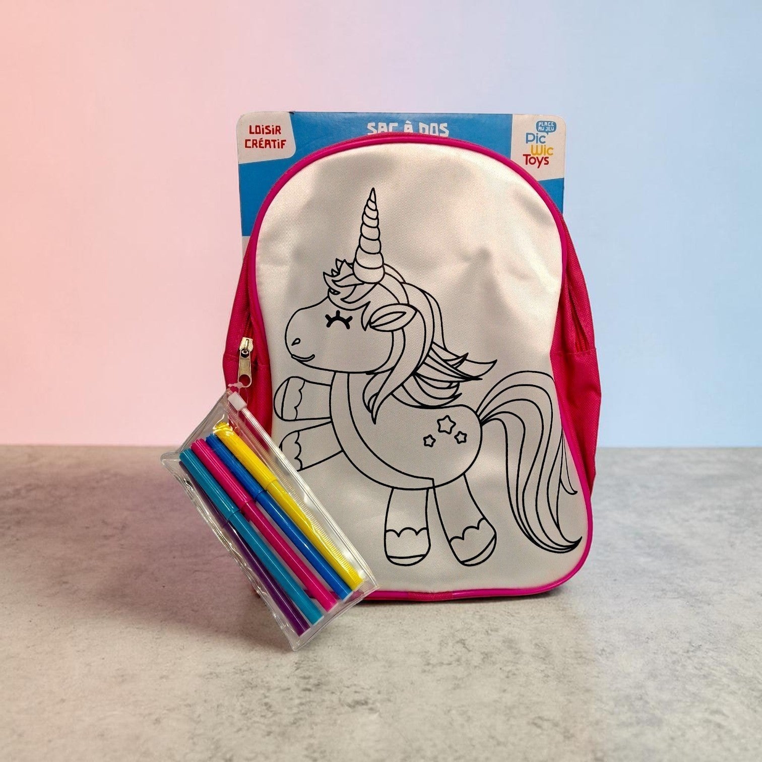 Tiny Tokens kids' white canvas backpack with a black unicorn outline, pink trim, and included fabric markers. Ideal for DIY art and school.