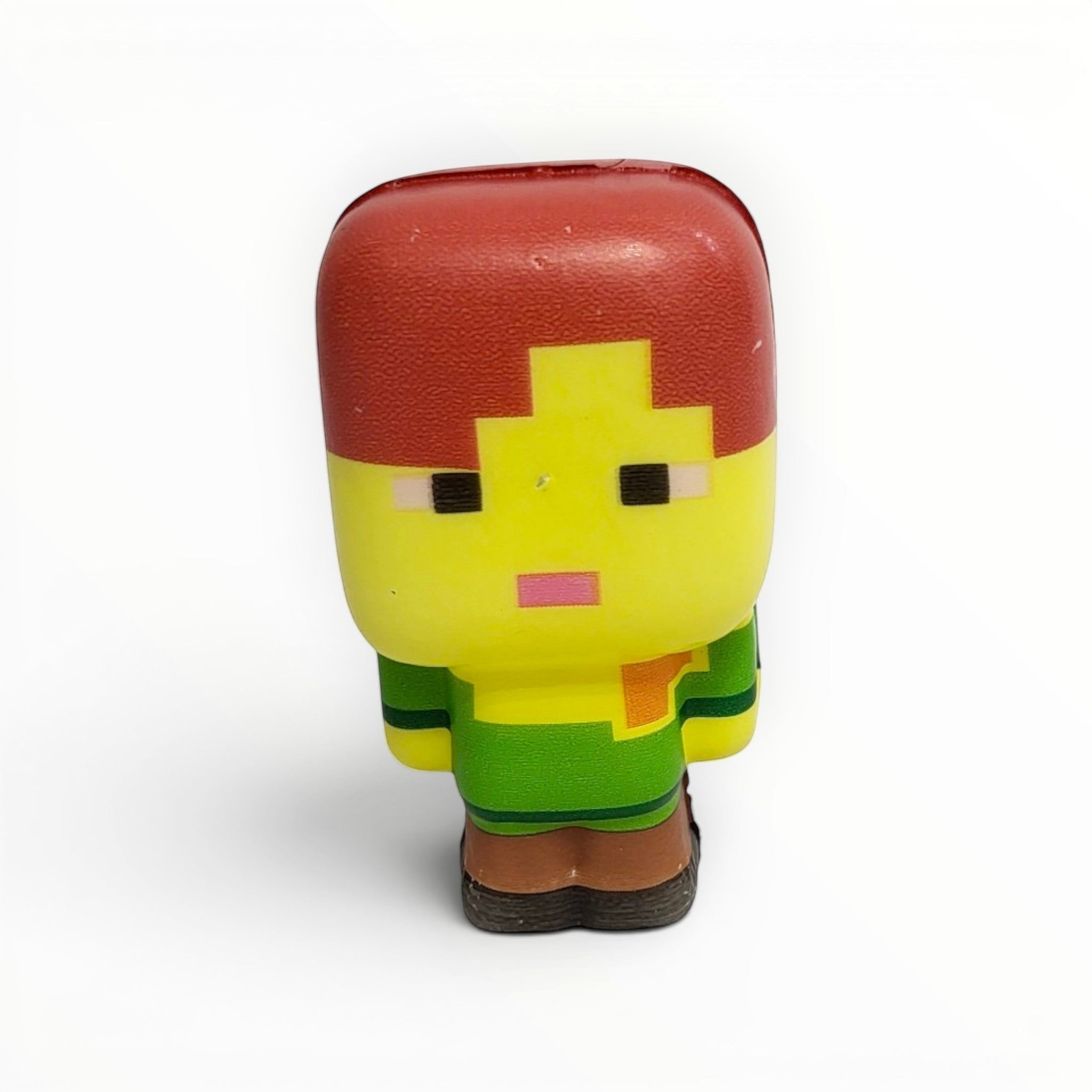 Tiny Tokens Minecraft-style pixel character squeeze toy, yellow face, red hair, green shirt, brown pants.