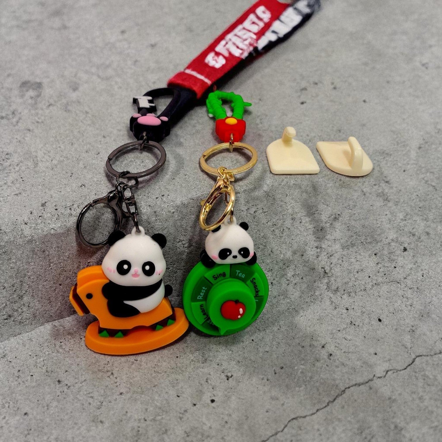 Tiny Tokens panda keychains: one on an orange rocking horse, another on a green spinner with text. Both have gold hardware.