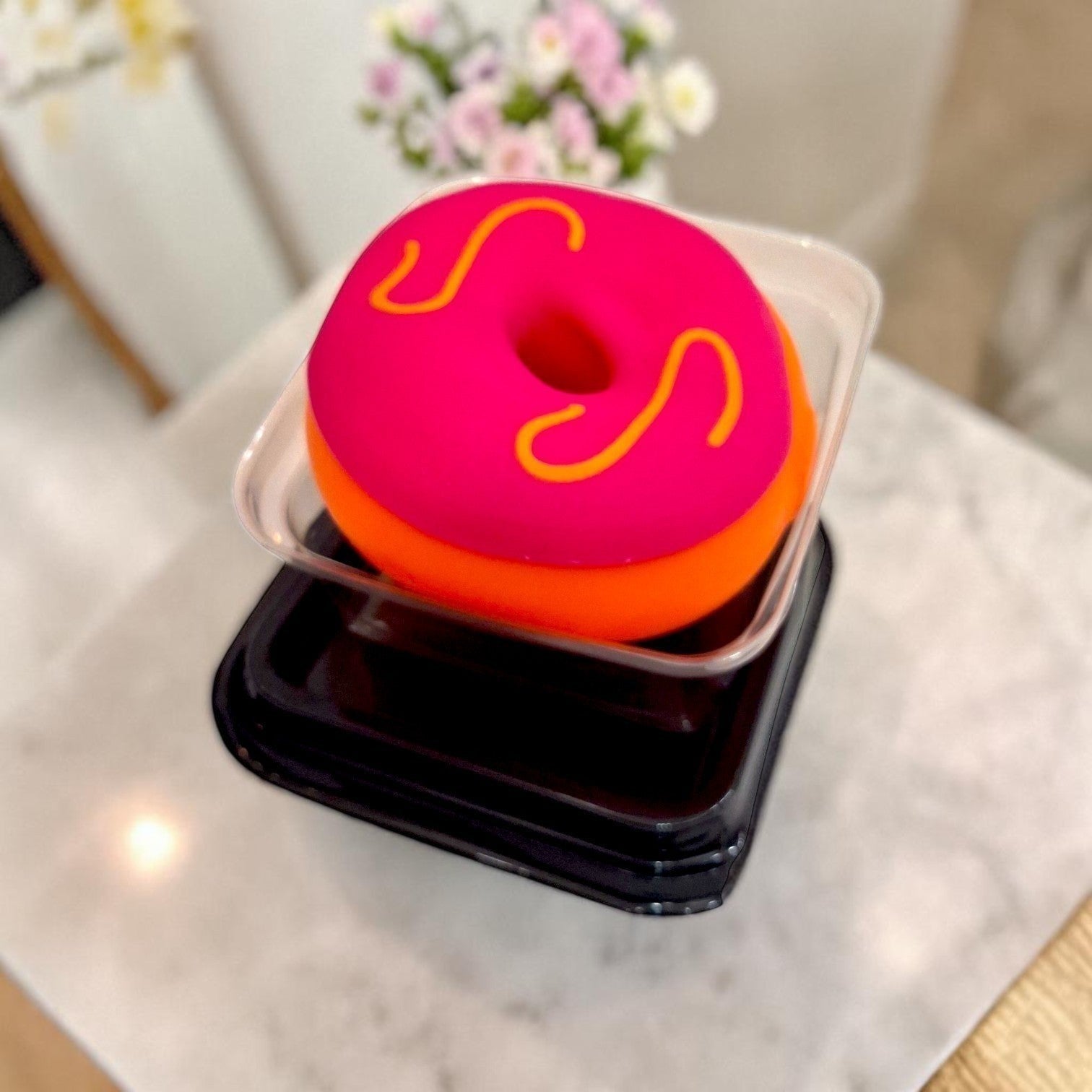 Tiny Tokens pink and orange donut squishy toy with yellow icing detail, made of soft silicone, presented in clear packaging.