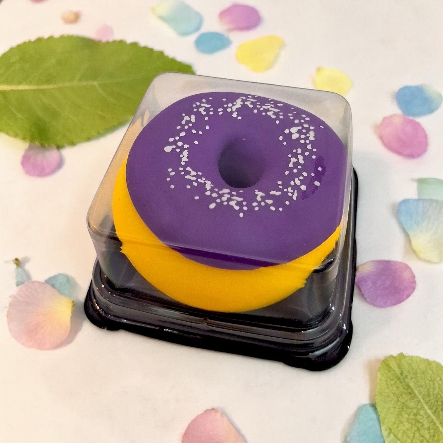 Tiny Tokens purple and yellow donut squishy toy with white sprinkles, made of soft silicone, in gift packaging.