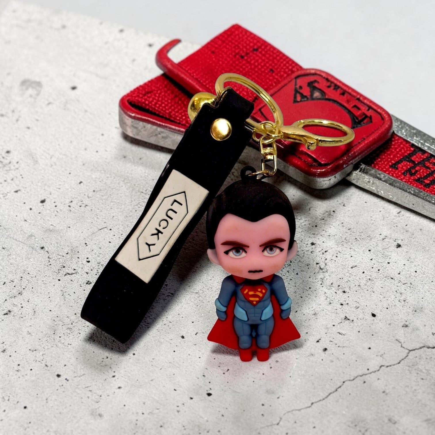 Tiny Tokens Superman 3D rubber keychain with black strap and gold hardware.