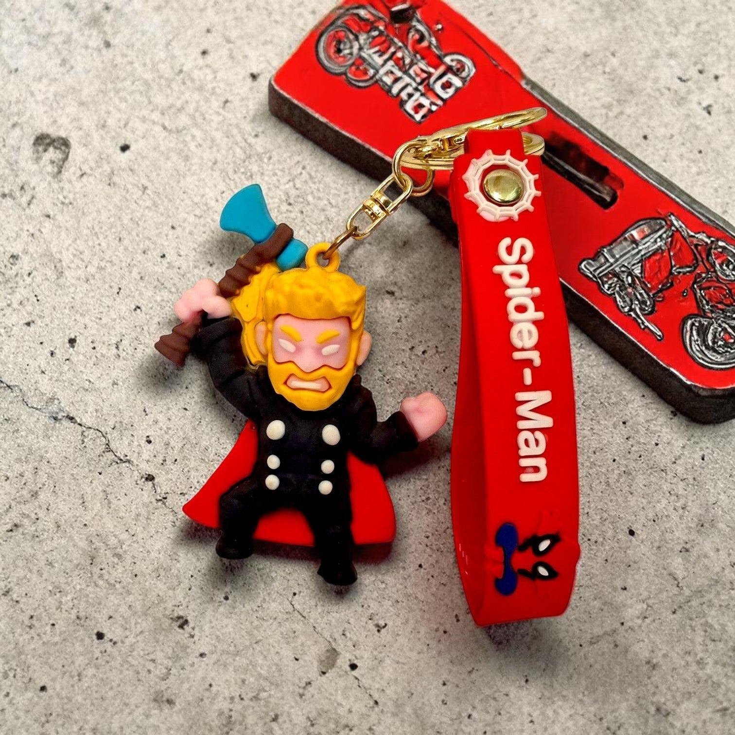 Tiny Tokens Thor 3D rubber keychain with red Spider-Man strap and gold hardware.